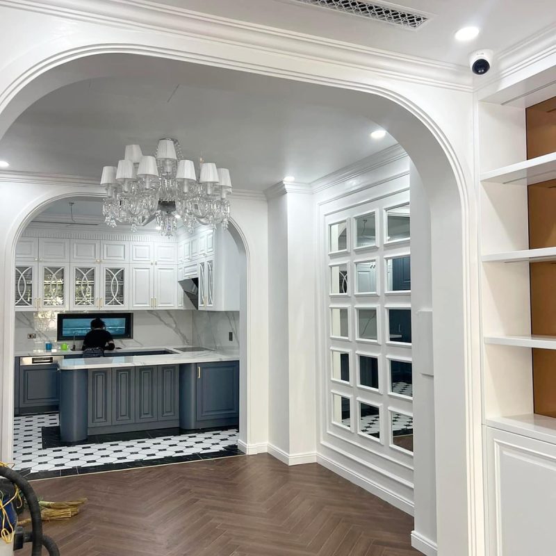 Tầm nhìn từ phòng khách qua vòm cửa cong Neo-classical sang trọng vào khu vực bếp và đảo bếp
